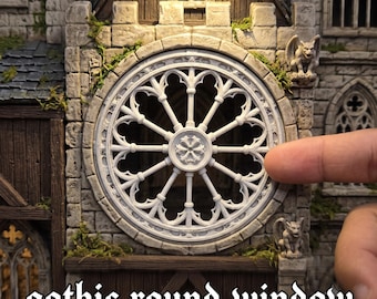 May include: A miniature gothic round window featuring intricate white stone-like tracery with a central floral motif, set into a textured gray stone wall with small green moss accents and two small stone gargoyle figures on the exterior.