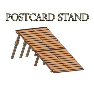 May include: A wooden postcard stand with the text "POSTCARD STAND" at the top. The stand is angled, with a slatted surface supported by angled legs. The wood has a natural finish.
