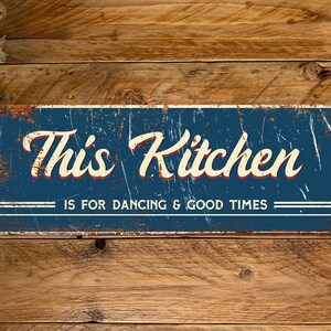 Könnte beinhalten: Ein blaues und weißes Metallschild mit dem Text "This Kitchen is for Dancing & Good Times". Das Schild hat einen abgenutzten, Vintage-Look.