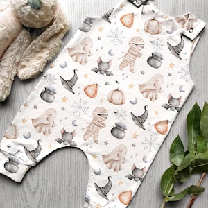 May include: White baby onesie with a Halloween theme. The onesie features a repeating pattern of ghosts, bats, pumpkins, witches hats, cauldrons, and mummies.