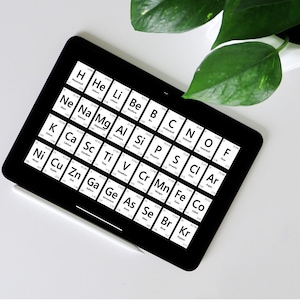 Könnte beinhalten: Ein schwarzes Tablet mit einem weißen Stift auf einer weißen Oberfläche. Der Tablet-Bildschirm zeigt ein Periodensystem der Elemente mit den Symbolen für die ersten 36 Elemente.