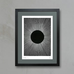 Könnte beinhalten: Schwarz-weiß-Druck einer Sonnenfinsternis mit strahlenden Linien. Der Druck ist in einem schwarzen Rahmen mit einer grauen Passepartout gerahmt. Der Druck ist mit "Eclipse" betitelt und mit "H.A.C." und "2022" signiert.