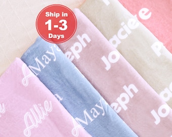 May include: Soft, pastel-colored blankets with personalized names in white script. The blankets are in shades of pink, blue, and beige. The text "Ship in 1-3 Days" is in a red circle.