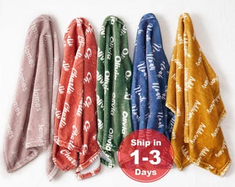 May include: Five soft plush blankets in dusty rose, terracotta, forest green, navy blue, and mustard yellow. Each blanket features a repeating white script pattern of a specific name: James, Charlie, Olivia, Noah, and Addison, respectively.