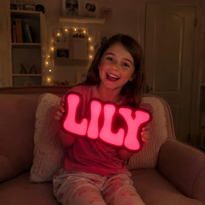 May include: A custom-made, illuminated sign featuring the name LILY in bold, rounded, capital letters. The sign emits a vibrant, glowing pink light, creating a bright focal point with its smooth, curved typography and modern, sleek design.