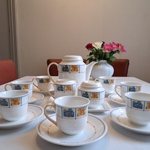 Può includere: Un set da tè in porcellana bianca con un motivo floreale blu e giallo. Il set comprende una teiera, un creamer, uno zuccheriera e sei tazze e piattini.