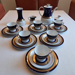 Peut inclure: Un service à thé en porcelaine bleu et blanc avec des accents dorés. L'ensemble comprend une théière, un pot à crème, un sucrier et six tasses et soucoupes.