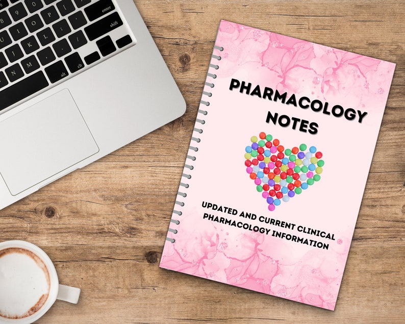 Pode incluir: Um caderno espiral rosa com o t&iacute;tulo "Pharmacology Notes" e um cora&ccedil;&atilde;o feito de p&iacute;lulas coloridas. O texto "Updated and Current Clinical Pharmacology Information" est&aacute; abaixo do cora&ccedil;&atilde;o.