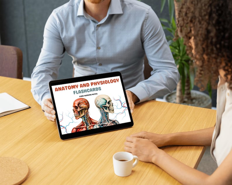May include: A digital tablet displaying a cover for Anatomy and Physiology Flashcards for future nursing notes. The cover features two illustrations of human skulls with red and blue veins.