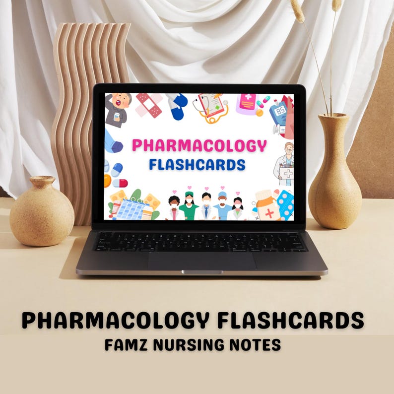 May include: A laptop computer screen displaying a colorful graphic with the text "Pharmacology Flashcards" and various medical illustrations. The laptop is on a light brown surface with a vase of dried flowers and a small vase with a brown ceramic pot.