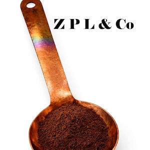 May include: A copper-colored scoop filled with dark brown powder, possibly coffee or a spice, against a white background. The text "ZPL & Co" is printed in black above the scoop.