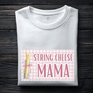 Könnte beinhalten: Weißes T-Shirt mit dem Text "STRING CHEESE MAMA" in Rosa. Das Design zeigt eine Illustration von Käsefäden in einem Glas mit einer rosa Schleife, vor einem rosa-weiß karierten Hintergrund.