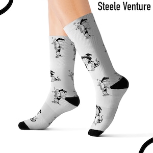 Puede incluir: Calcetines blancos con un patrón repetitivo en blanco y negro de un lagarto con un sombrero de mago y sosteniendo una varita mágica. El texto "Steele Venture" está impreso en la parte superior de los calcetines.
