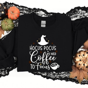May include: Black sweatshirt with a white graphic that says "Hocus Pocus I Need Coffee To Focus" with a witch's hat and a coffee cup.