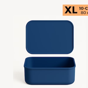 Può includere: Un contenitore per alimenti blu navy XL con coperchio abbinato. Il contenitore è rettangolare con angoli arrotondati. Il coperchio è leggermente rialzato sopra la base. Il testo in alto a destra recita "XL 10-Cup 80 oz".