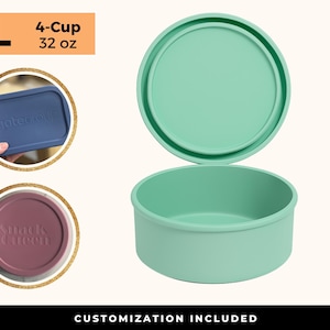 May include: A mint green, 4-cup (32 oz) round food container with a matching lid. The lid is slightly ajar, revealing the interior. Two additional lids are shown, one blue with the text "gate group" and one maroon with the text "Snack Queen". The words "CUSTOMIZATION INCLUDED" are at the bottom.