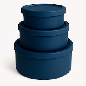 May include: Three navy blue nesting containers stacked. Each round container has a matching lid. The containers are made of a solid material with a matte finish. The containers are different sizes. The containers are in shades of blue.