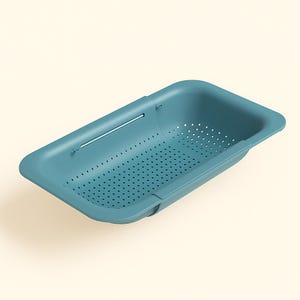 Puede incluir: Un escurridor rectangular de color turquesa con numerosos agujeros de drenaje pequeños. Cuenta con un asa de barra metálica y está diseñado para encajar sobre un fregadero. El escurridor está hecho de plástico duradero.