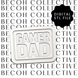 Peut inclure: Un panneau rectangulaire blanc aux coins arrondis, avec les mots "GAMER DAD" en gras, en police sans-serif. Le fond est un motif répété des mots "BECOH COLLECTIVE". Une forme noire avec le texte "DIGITAL STL FILE" est en haut à droite.