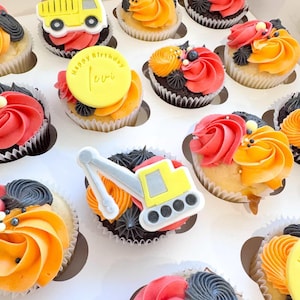 May include: A box of cupcakes with colourful frosting and decorative toppers. Some cupcakes feature yellow construction vehicles, others have a yellow disc with "Happy Birthday Levi" text, and some have a number 2.