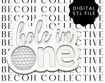 Puede incluir: Un diseño blanco con temática de golf con las palabras "hole in one" y un gráfico de pelota de golf. El diseño es un archivo STL digital. El fondo presenta las palabras "BECOH COLLECTIVE".