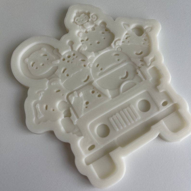 May include: White silicone mold of a cartoon jeep with animal passengers. The jeep has a grill, headlights, and wheels. The animals are a monkey, a tiger, a zebra, and a hippo.