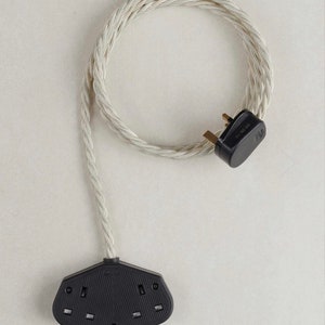 May include: A white braided electrical extension lead with a three-pin plug on one end and a three-gang adapter on the other end.