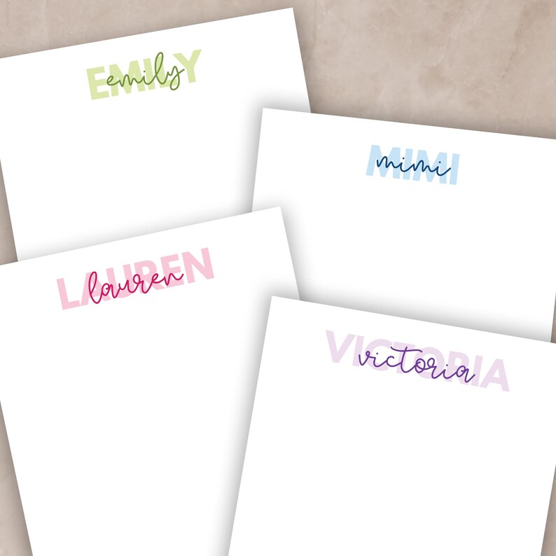 May include: Four white notepads with names printed in various colours. The names are Emily in green, Mimi in blue, Lauren in pink, and Victoria in purple. The names are in a handwritten style font.