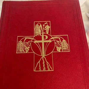 May include: A red hardback book with a gold embossed cross design. The cross is surrounded by wheat and grapes.