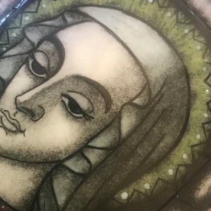 Puede incluir: Un primer plano de una pintura que representa el rostro de una mujer. La mujer tiene el pelo oscuro y lleva una túnica oscura. La pintura está realizada en un estilo estilizado, casi de dibujos animados, con líneas y colores audaces. El fondo es de color verde oscuro con un patrón de puntos blancos.