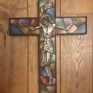 Może przedstawiać: Szklana mozaika przedstawiająca Jezusa Chrystusa na drewnianym krzyżu. Krzyż jest oprawiony w brązowe drewno, a szkło zdobi kolorowy wzór mozaiki. Na szczycie krzyża widoczny jest napis "INRI".