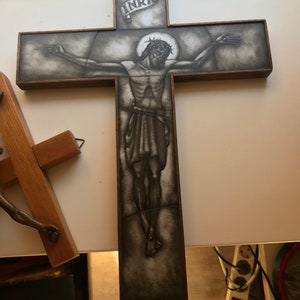 Może przedstawiać: Drewniany krucyfiks z czarno-białym obrazem Jezusa Chrystusa na krzyżu. Obraz jest otoczony brązową ramą. Na krzyżu widoczny jest napis "INRI".