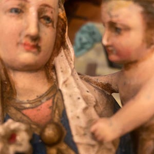 Puede incluir: Una estatua vintage de la Virgen María y el niño Jesús. La estatua está hecha de yeso pintado y presenta un diseño detallado. La Virgen María lleva una túnica azul con detalles dorados y un velo blanco. El niño Jesús lleva una corona y una túnica blanca.