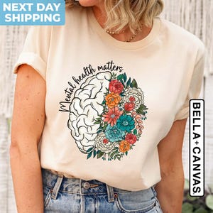 May include: A beige t-shirt with the text "Mental health matters" printed on the front. The text is surrounded by a stylized brain with flowers.