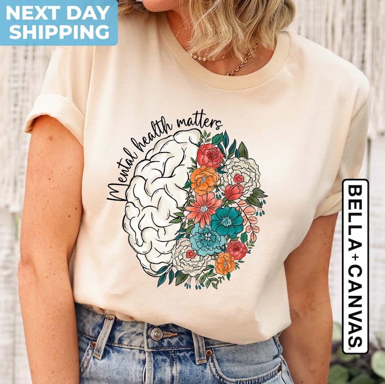 May include: A beige t-shirt with the text "Mental health matters" printed on the front. The text is surrounded by a stylized brain with flowers.