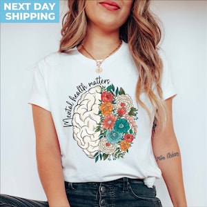 May include: White t-shirt with a graphic of a brain with flowers on one side and the text "Mental health matters" on the other side.