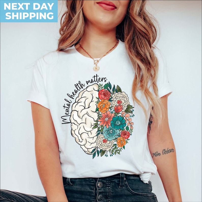 May include: White t-shirt with a graphic of a brain with flowers on one side and the text "Mental health matters" on the other side.