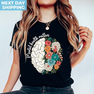 May include: Black t-shirt with a white brain outline filled with colorful flowers. The text "Mental health matters" is written around the brain.