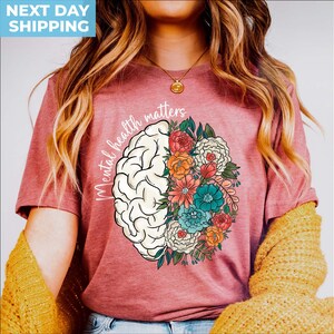 May include: A pink t-shirt with the text "Mental health matters" and a stylized brain with flowers on it.