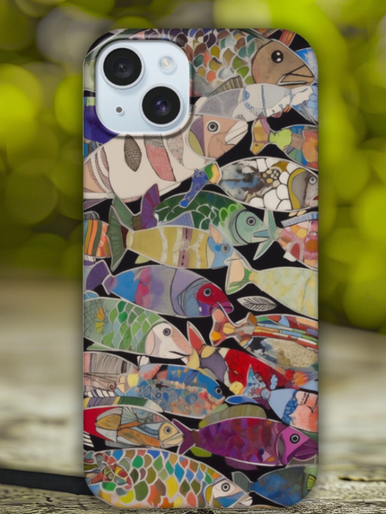 Puede incluir: Una funda para tel&eacute;fono con un dise&ntilde;o colorido de peces sobre un fondo negro. La funda tiene un recorte para la c&aacute;mara y un borde blanco.