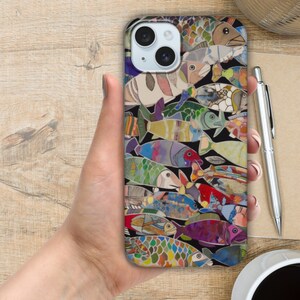 Puede incluir: Una funda de tel&eacute;fono colorida con un patr&oacute;n de peces. Los peces est&aacute;n hechos de diferentes materiales y colores, y est&aacute;n dispuestos en un patr&oacute;n aleatorio. La funda est&aacute; dise&ntilde;ada para un iPhone.