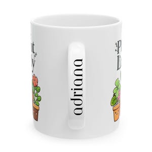 Peut inclure: Une tasse en c&eacute;ramique blanche avec une illustration de plante noire et verte et le texte "Plant Lady" d'un c&ocirc;t&eacute; et le nom "Adriana" de l'autre.