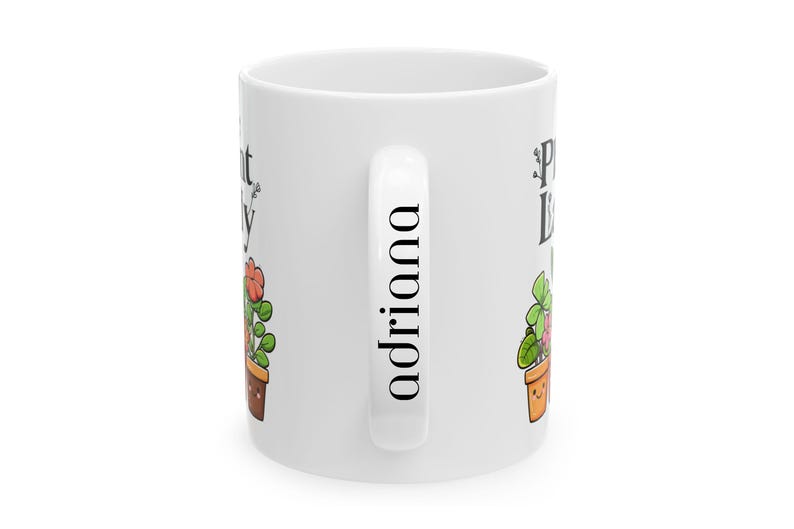 Peut inclure: Une tasse en c&eacute;ramique blanche avec une illustration de plante noire et verte et le texte "Plant Lady" d'un c&ocirc;t&eacute; et le nom "Adriana" de l'autre.