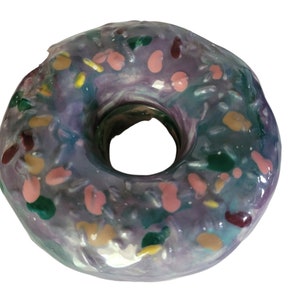 Può includere: Un ciambellone glassato viola con codette colorate. Il ciambellone ha un buco al centro ed è ricoperto da una glassa lucida.