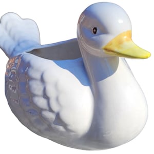 Puede incluir: Maceta de cerámica blanca en forma de pato con un pico amarillo y un pequeño agujero en la parte superior para plantar.