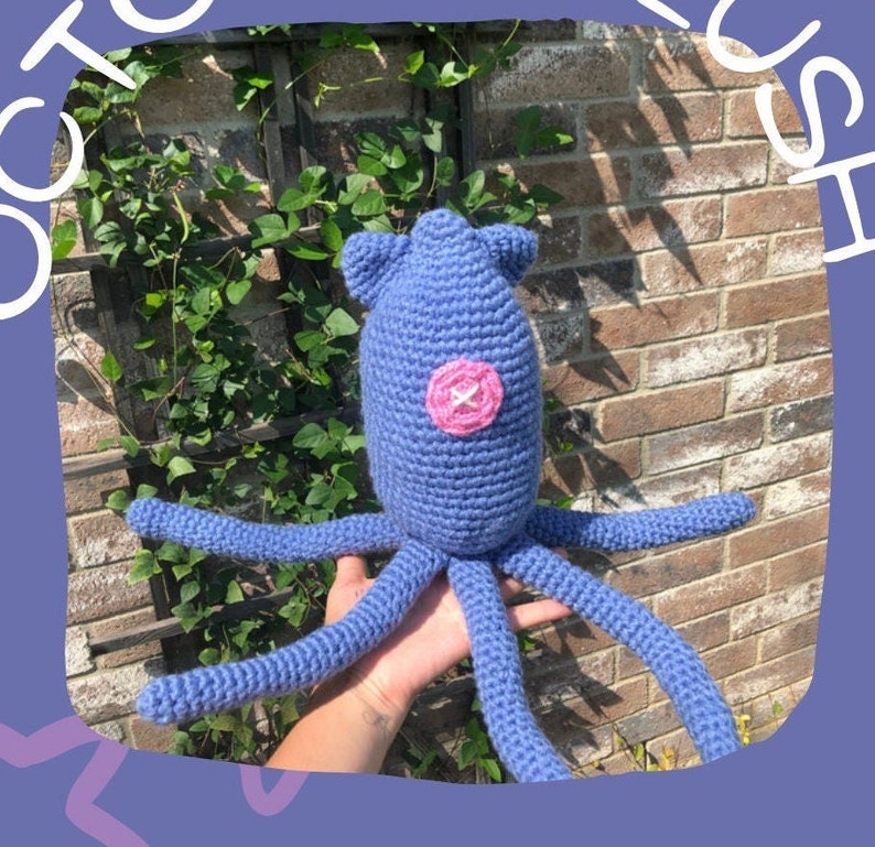May include: A crocheted octopus plush toy in a light blue colour with a pink button for an eye. The octopus has eight tentacles.