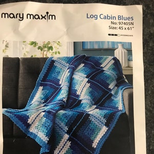 May include: A crocheted blanket in shades of blue, white, and teal, draped over a dark gray couch. The blanket features a geometric "Log Cabin" design, measuring 45 x 61 inches. The pattern is labeled "Log Cabin Blues" and is designed by Dorothy Warrell.