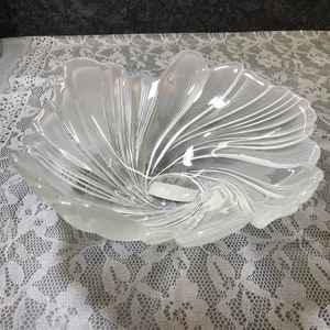 Puede incluir: Un cuenco de vidrio transparente con un dise&ntilde;o de espiral. El cuenco tiene forma de flor y tiene una abertura ancha y poco profunda.