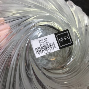 Puede incluir: Un cuenco de vidrio transparente con un dise&ntilde;o en espiral. El cuenco est&aacute; etiquetado con "SPUN SILK BOWL 9 3/4" y "SA 137/725" con un c&oacute;digo de barras y "Alemania" impreso en la etiqueta. La etiqueta tambi&eacute;n incluye el logotipo de Mikasa.