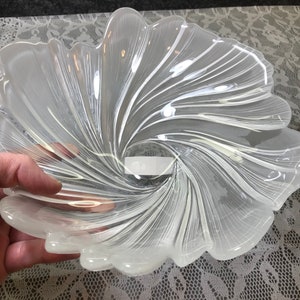 Puede incluir: Un cuenco de vidrio transparente con un dise&ntilde;o de espiral. El cuenco tiene forma de flor con m&uacute;ltiples p&eacute;talos.